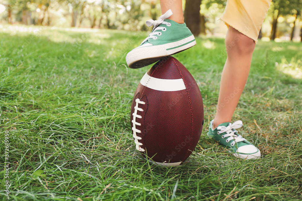 Little boy playing American football outdoors