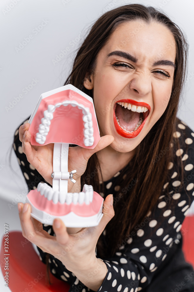 Model of artificial jaw with teeth in hands. Dentist cabinet background. Dentistry concept.