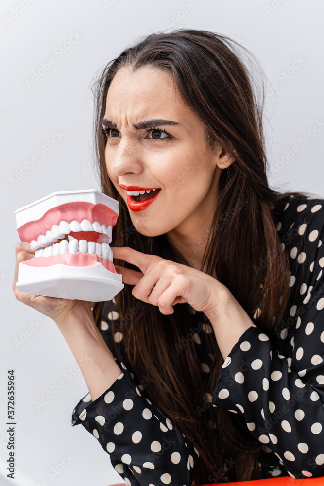 Woman with surprised face and opened mouth. Young girl holding opened educational dentist jaw near f