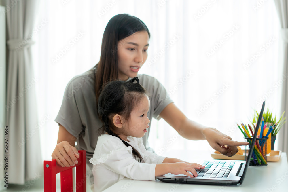 亚洲幼儿园女孩与母亲在李与老师在笔记本电脑上进行视频会议电子学习