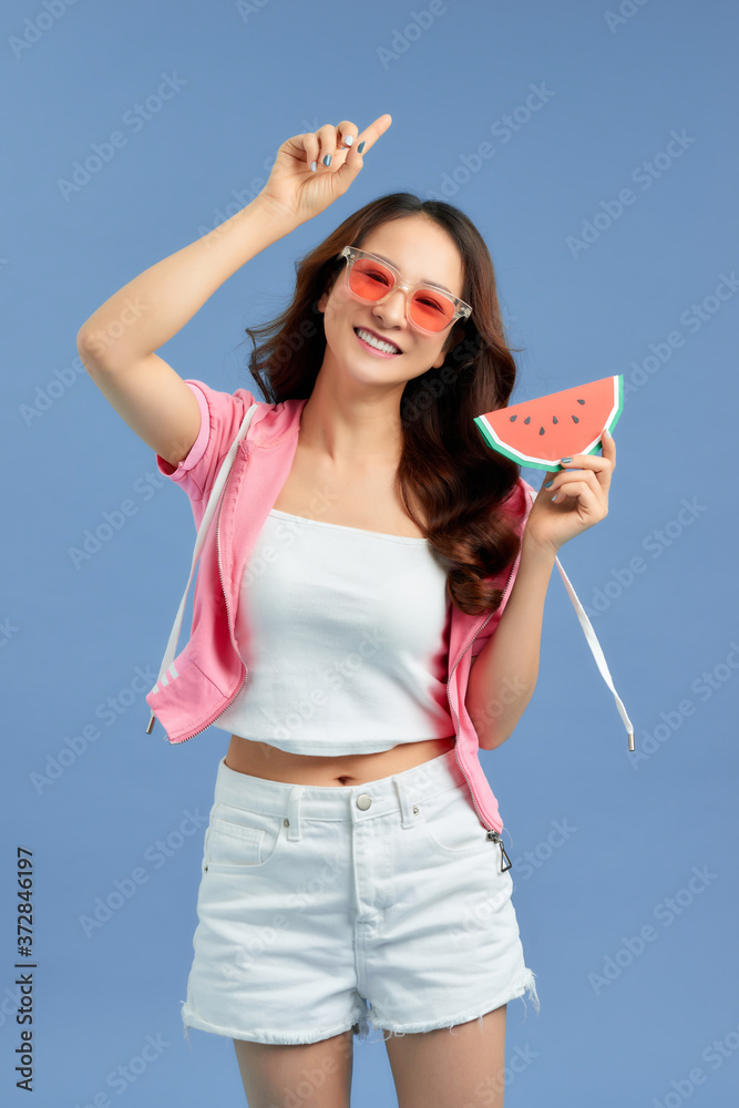 Portrait happy woman is holding slice of watermelon over colorful blue background