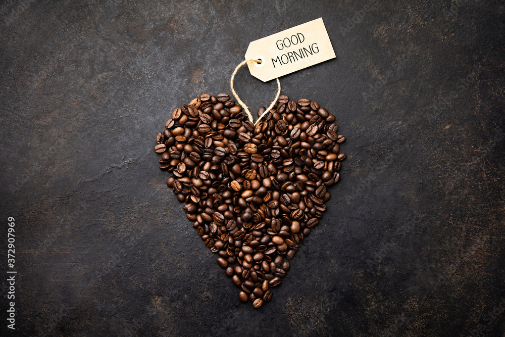 Coffee beans in shape of heart on dark rustic background