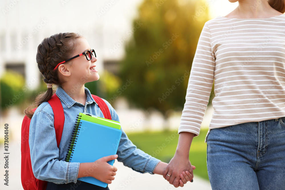 快乐的女学生和妈妈一起走向学校。