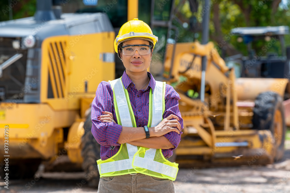 自信的女建筑师在施工现场戴着安全帽，穿着反光背心的肖像。