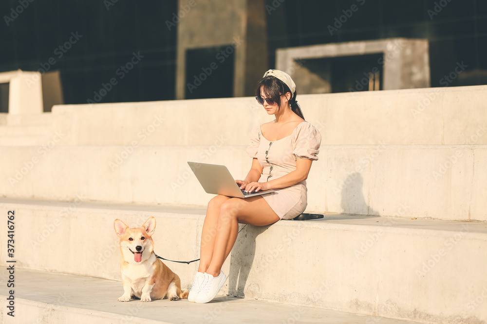 带着可爱的柯基犬在户外散步的女人