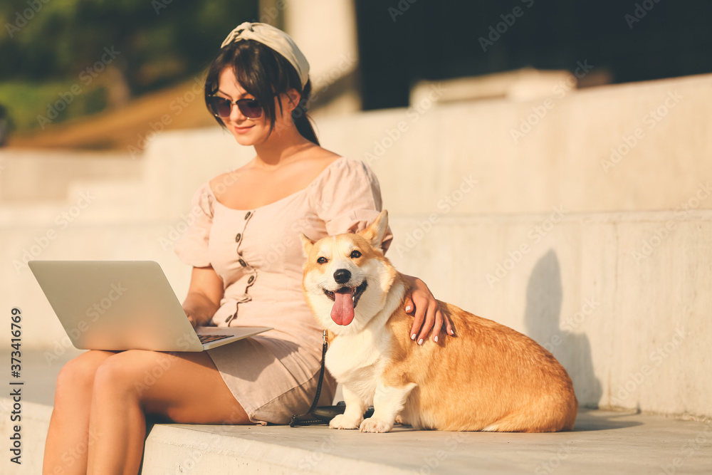 带着可爱的柯基犬在户外散步的女人