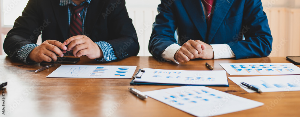 Two business people work at their desks and business analysis report papers.