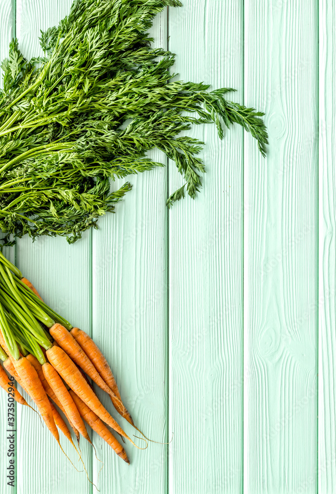 Bunch of fresh carrots with green tops form above copy space