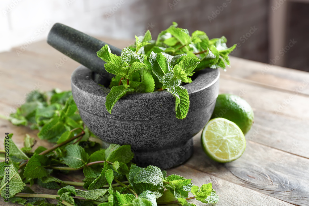 Mortar with fresh mint, lime and pestle on table