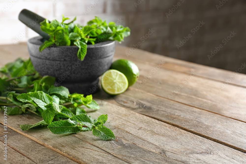 Mortar with fresh mint, lime and pestle on table