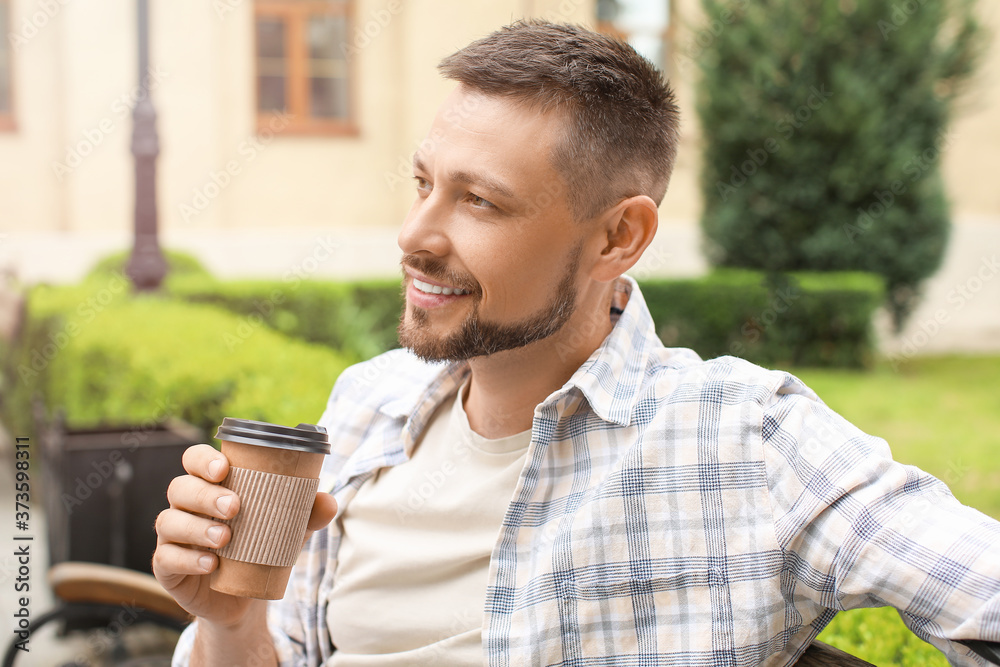 Handsome man drinking coffee while relaxing in park