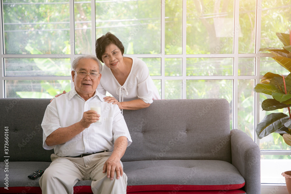 Smiling asian senior couple drinking milk at home.