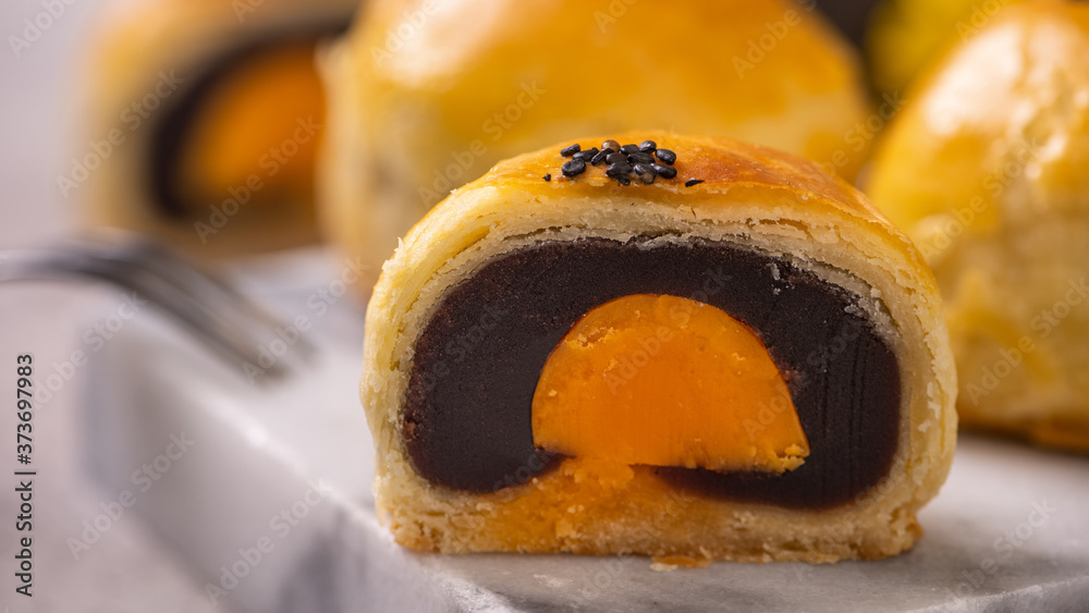 Tasty baked egg yolk pastry moon cake for Mid-Autumn Festival on bright cement table background. Chi