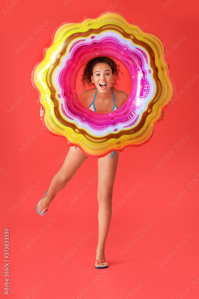 Beautiful young African-American woman with inflatable ring on color background