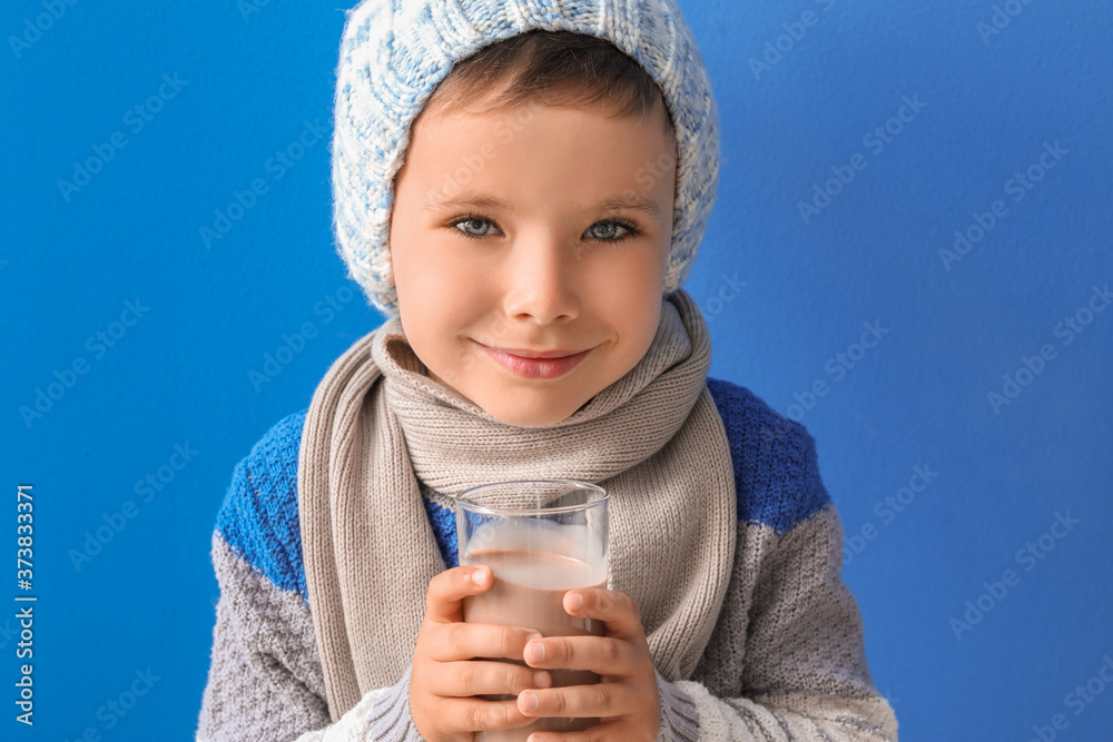 Little boy with tasty chocolate milk on color background