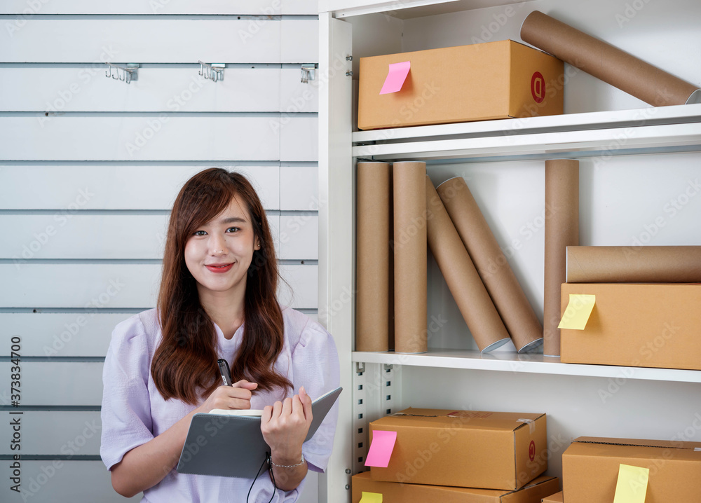 Young asian small business owner at a home office is checking stock of products for prepackaged cust