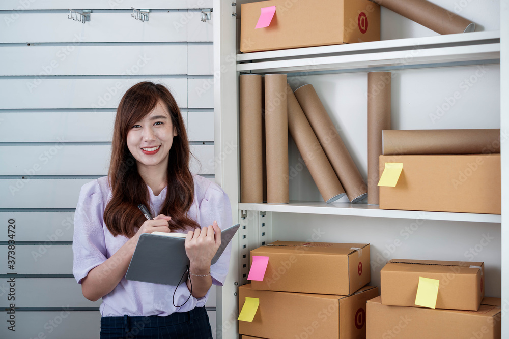 Young asian small business owner at a home office is checking stock of products for prepackaged cust