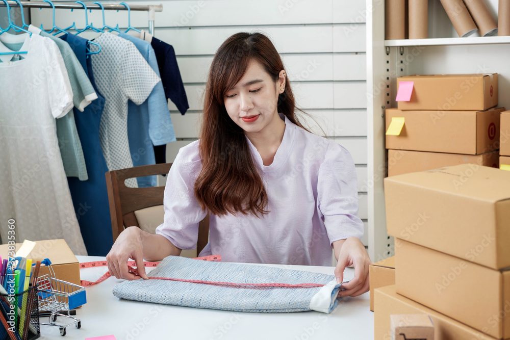 一位亚洲女企业家在为交付产品做准备时测量裙子尺寸的肖像