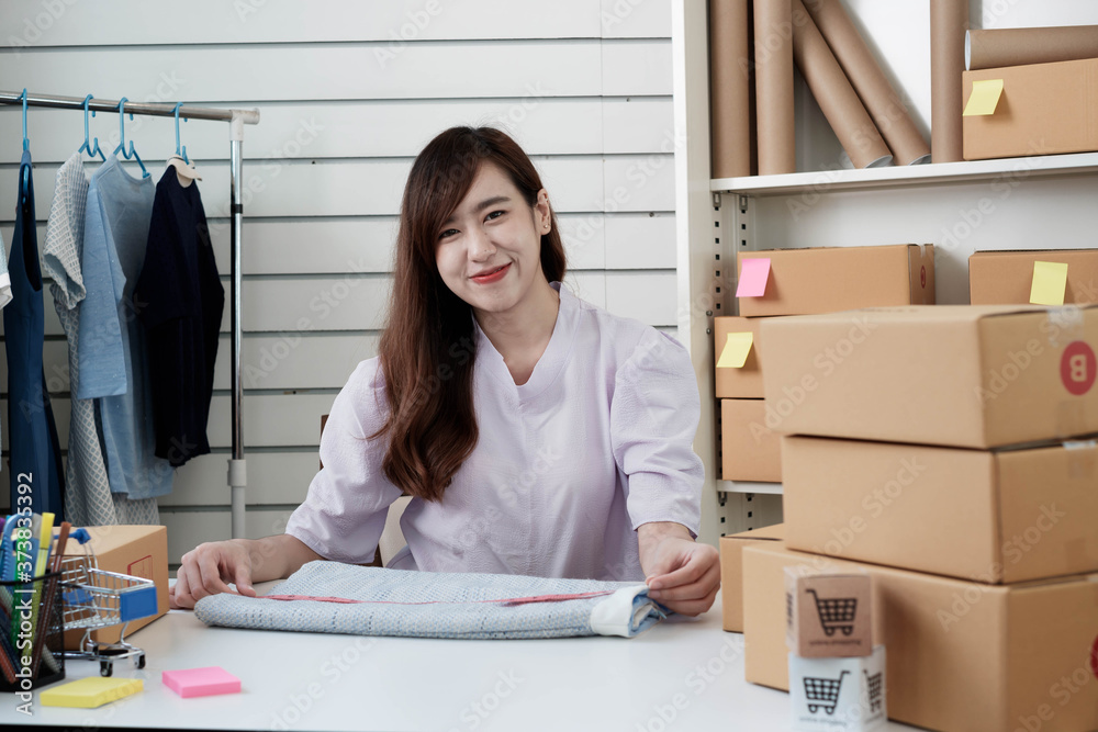 Portrait of an Asian female entrepreneur measuring skirt sizing in preparation for delivery of produ