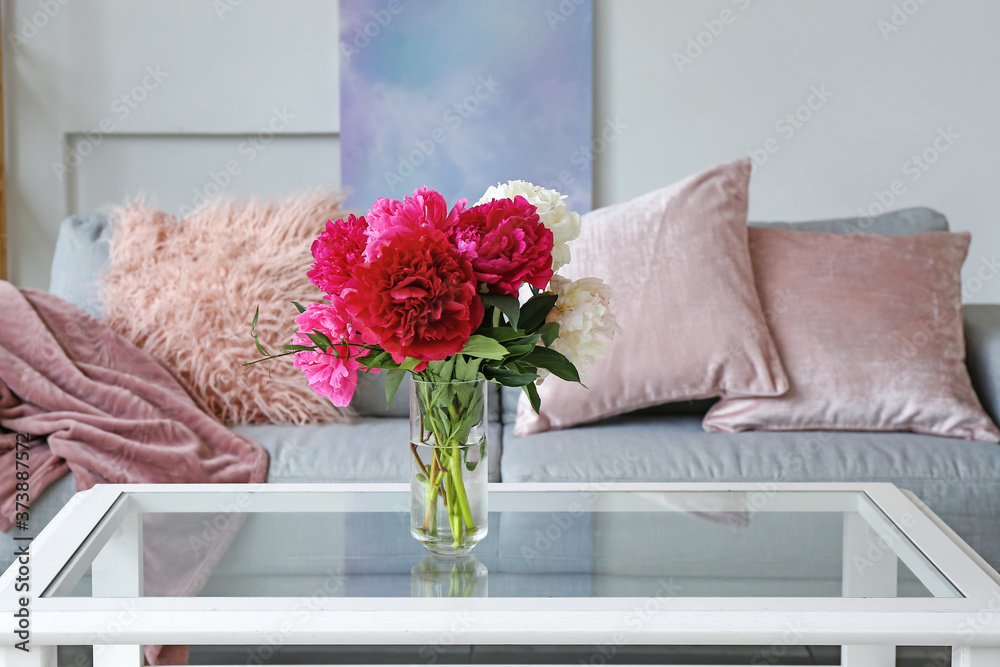 Stylish interior of living room with table, bouquet of flowers and sofa