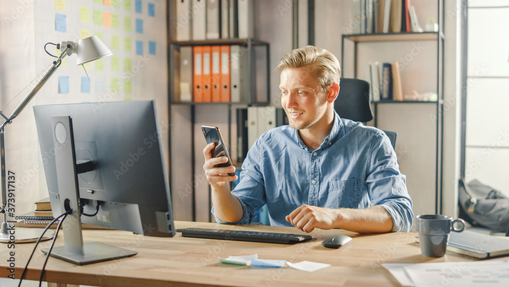 Creative Entrepreneur Sitting at His Desk Works on Desktop Computer in Stylish Office, Picks up and 