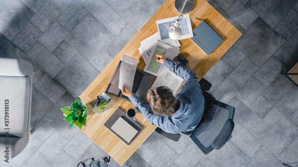 Businessman Sitting at His Desk in the Office Uses Laptop Computer, Working with Company Strategy Do