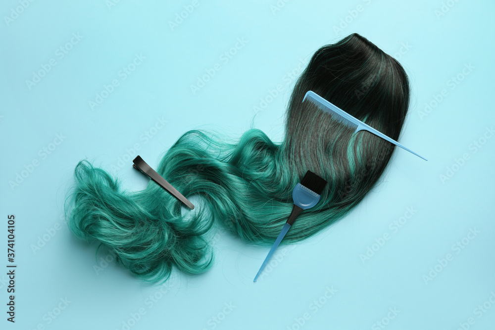 Unusual wig with hairdresser supplies on color background