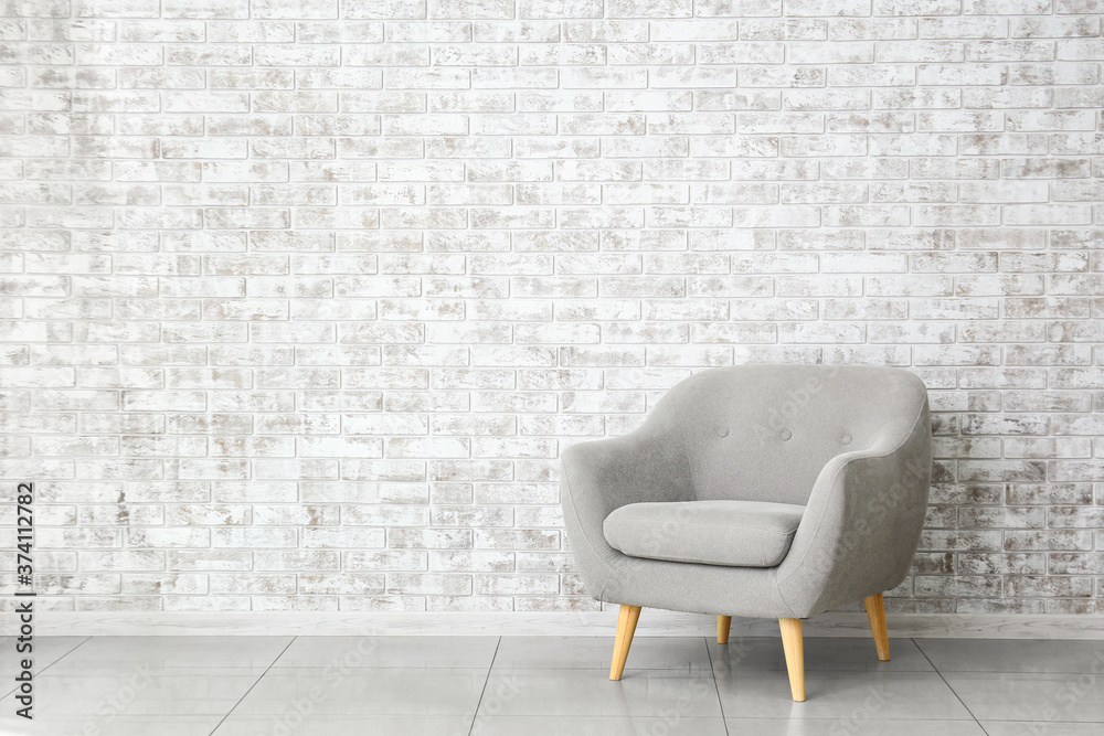 Modern armchair near brick wall in room