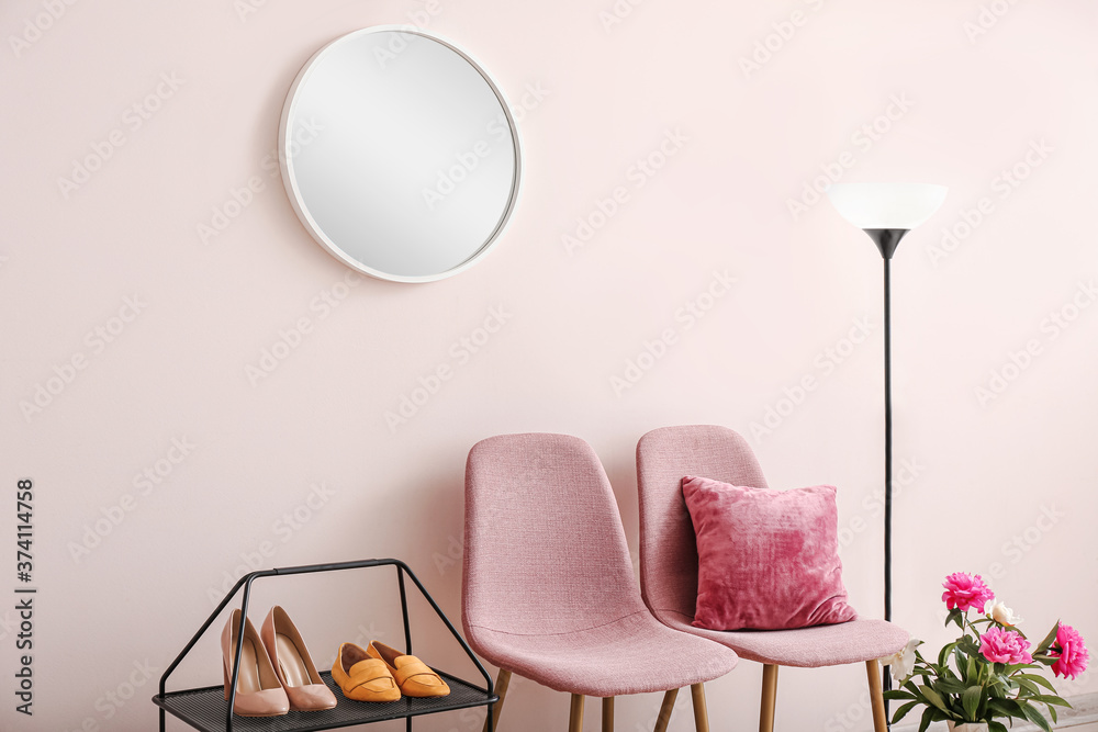 Stylish interior of hallway with shoe stand, chairs and mirror