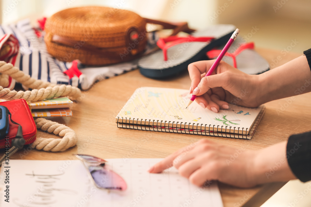 Woman making check-list of things to pack for travel