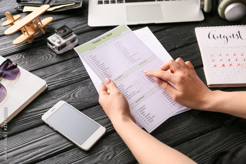 Woman making check-list of things to pack for travel