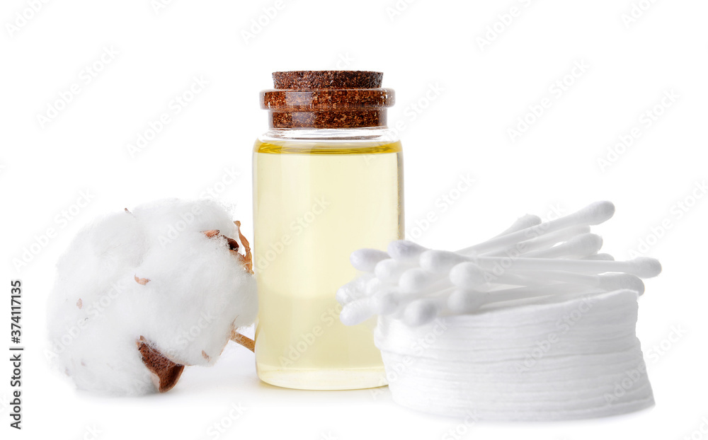 Bottle of cottonseed oil with cosmetic pads and sticks on white background