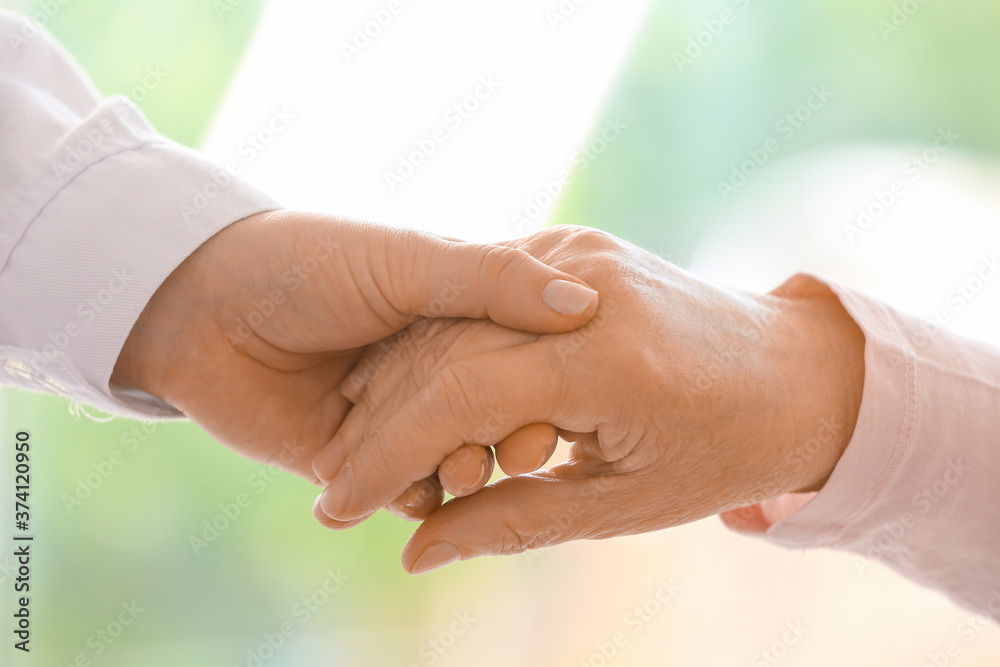 Hands of senior woman and caregiver, closeup