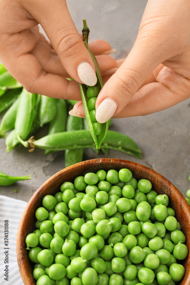 Woman preparing fresh peas on table, closeup