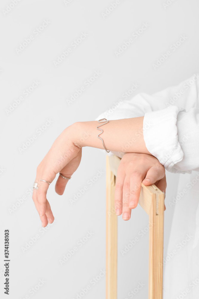 Beautiful young woman wearing stylish jewelry on light background