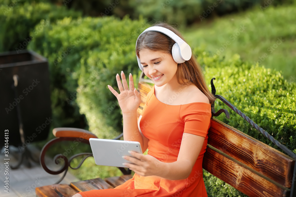 Teenage girl with tablet computer listening to music in park