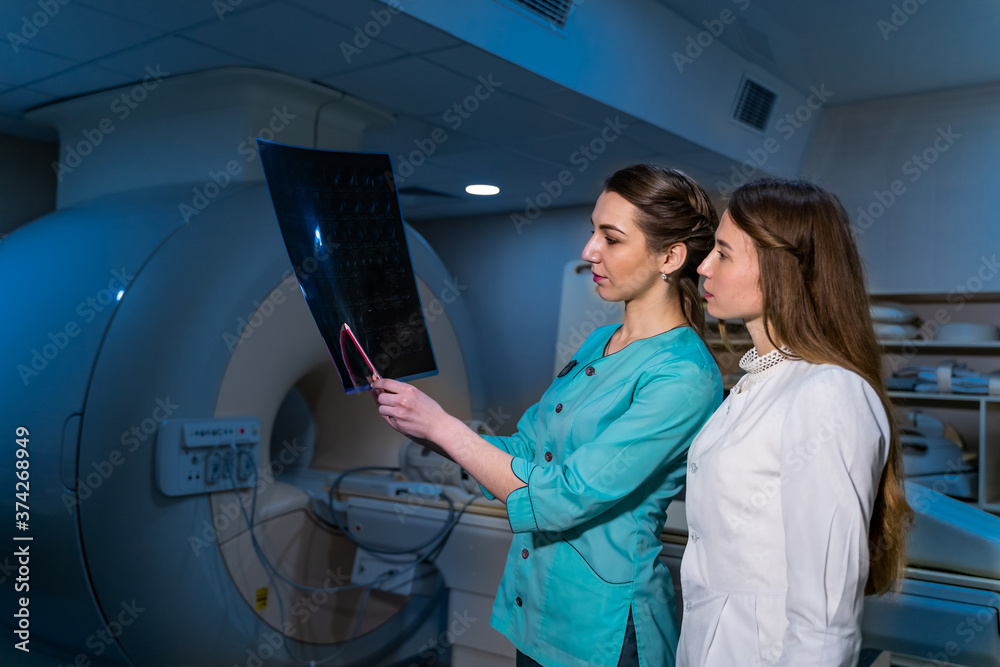 Two female women medical doctors looking at x-rays in a hospital. Neurosurgery concept.