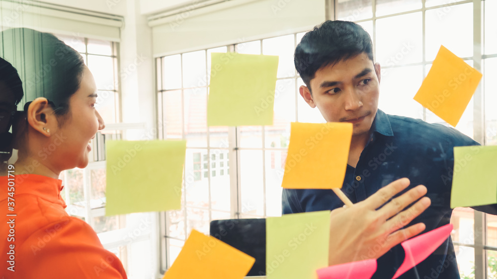 Business people work on project planning board in office and having conversation with coworker frien