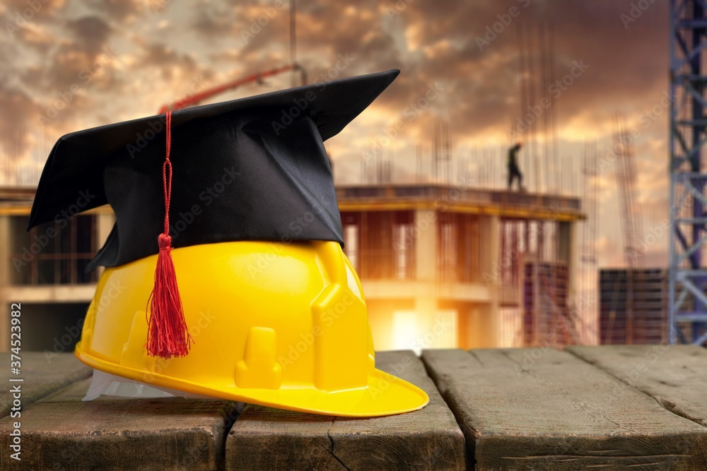 Yellow worker helmet with graduation hat on the construction