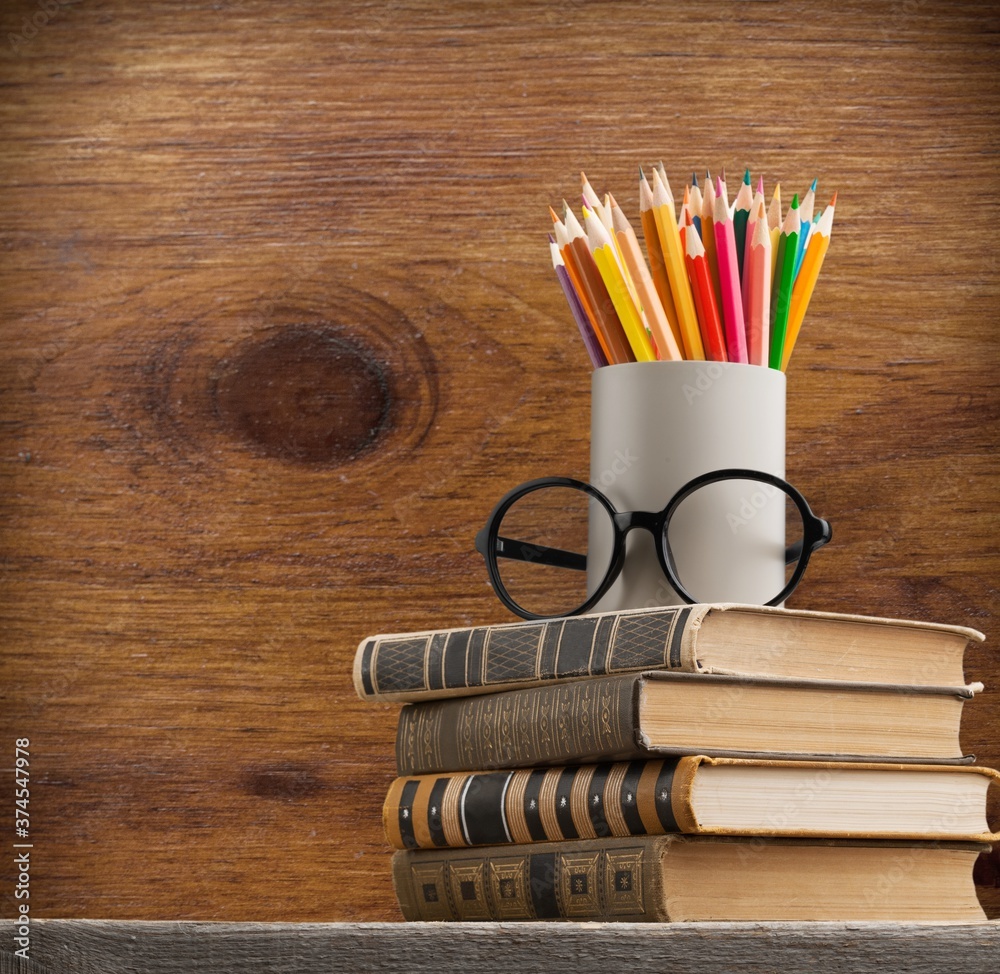 Stack of vintage books and colorful pencils on the desk