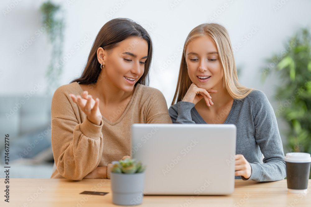 two happy young women using laptop