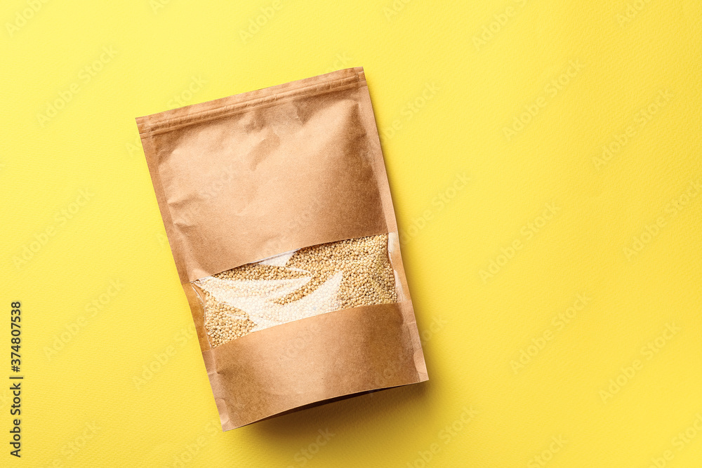 Bag with healthy quinoa on color background