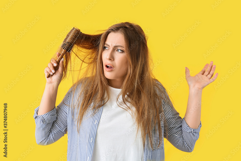 Stressed woman brushing hair on color background