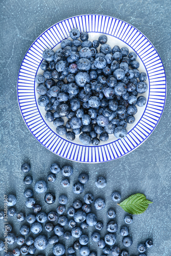 Plate with tasty blueberry on grey background