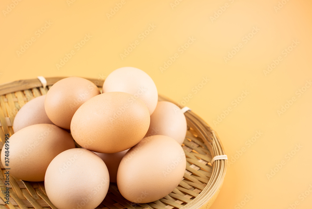 Eggs in a bamboo basket on yellow background