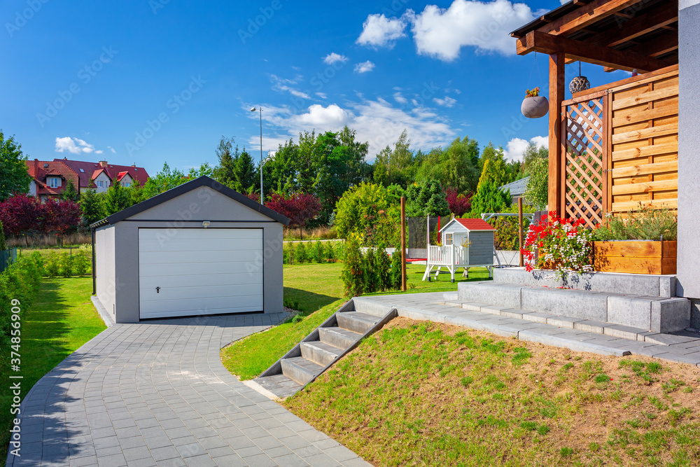 Driveway to the garage in the sunny garden at the house