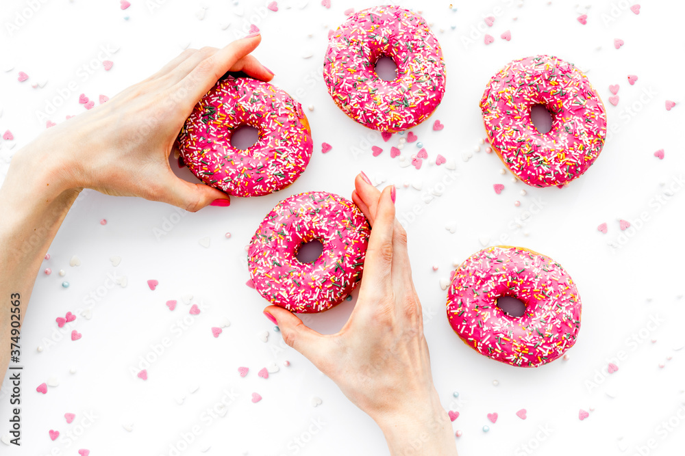 Hand holding donut with icing and sprinkles. Flat lay, top view