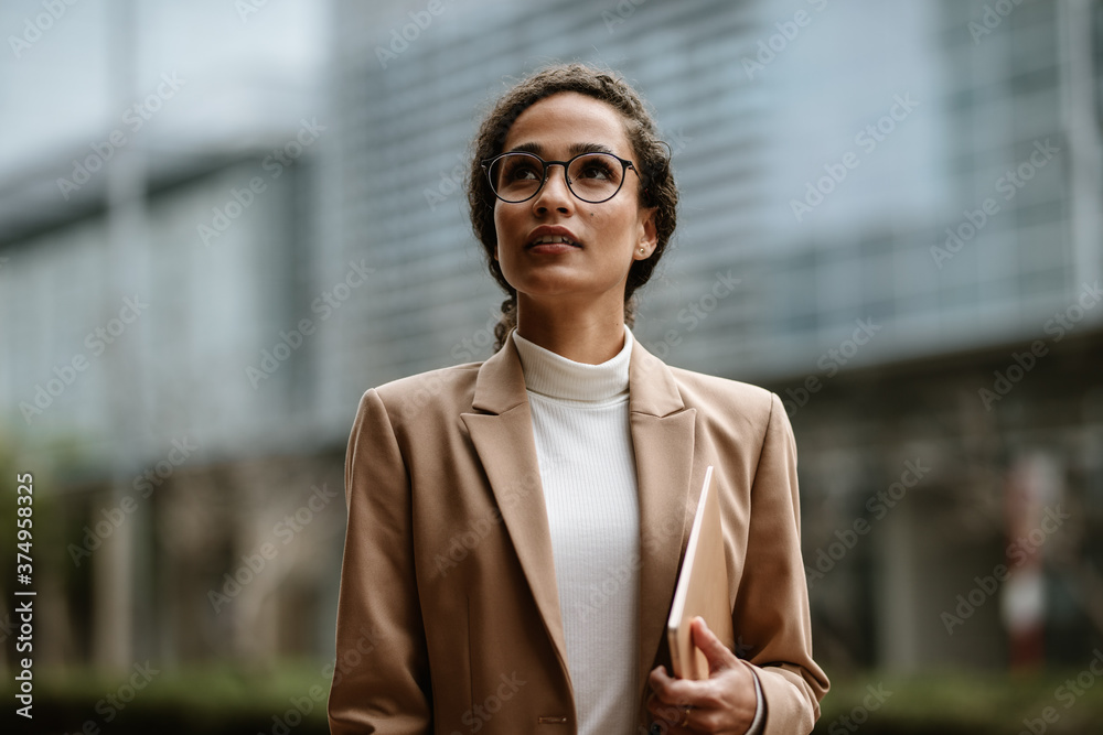 拿着数字平板电脑在户外行走的女商人