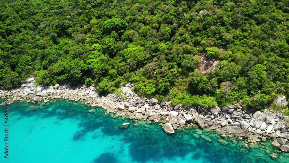 热带火山岛附近平静的大海。石头海岸附近平静的蓝色海水的无人机视图。