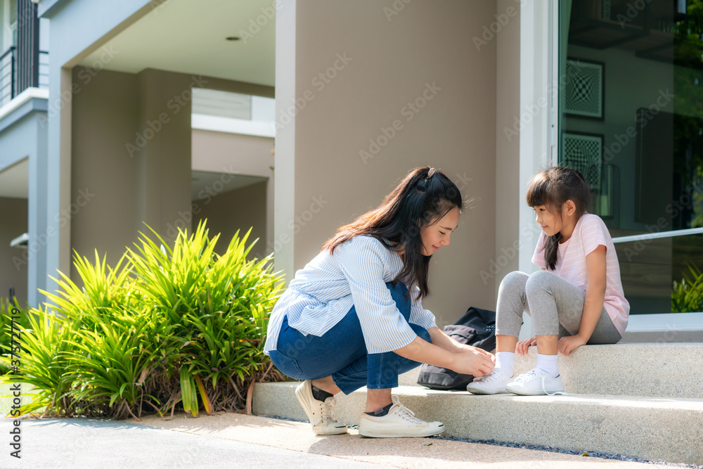 亚洲母亲帮助女儿穿制服的小学生系鞋带